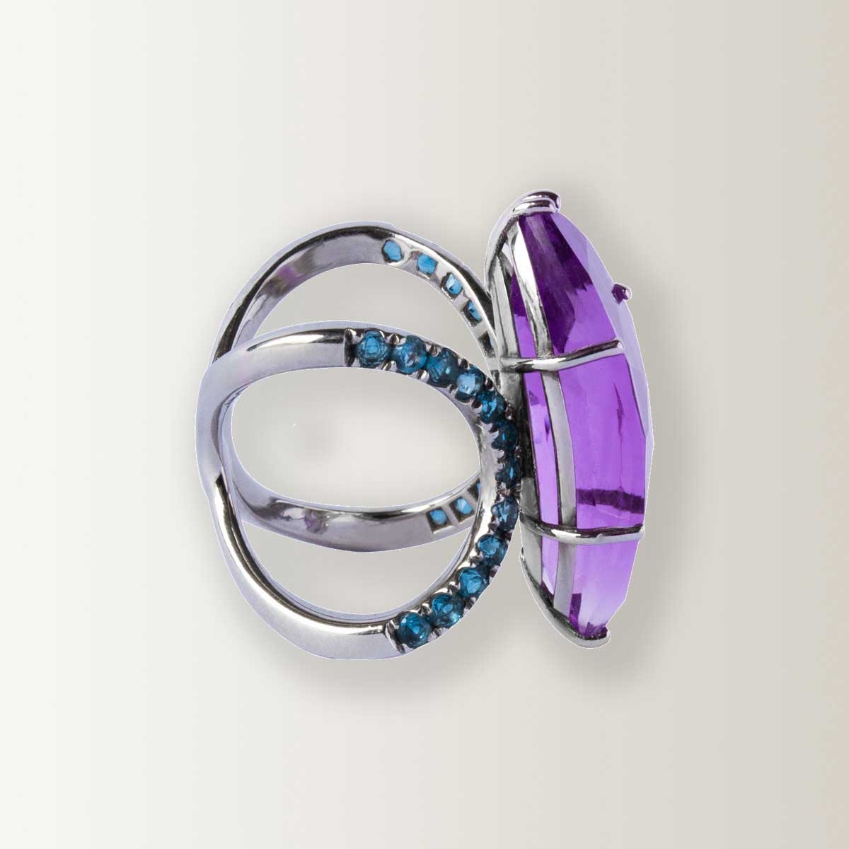 Anillo doble circulo de oro blanco, topacios azules London Blue redondos, y amatista central talla navette fantasía.