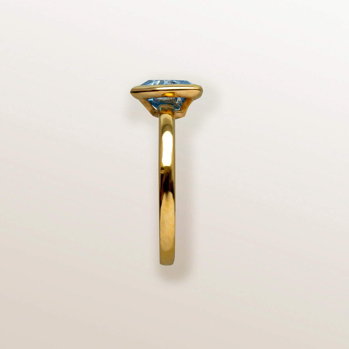 Mano con Anillo de Oro Vermeil amarillo, y topacio azul natural tallado en forma triangular
