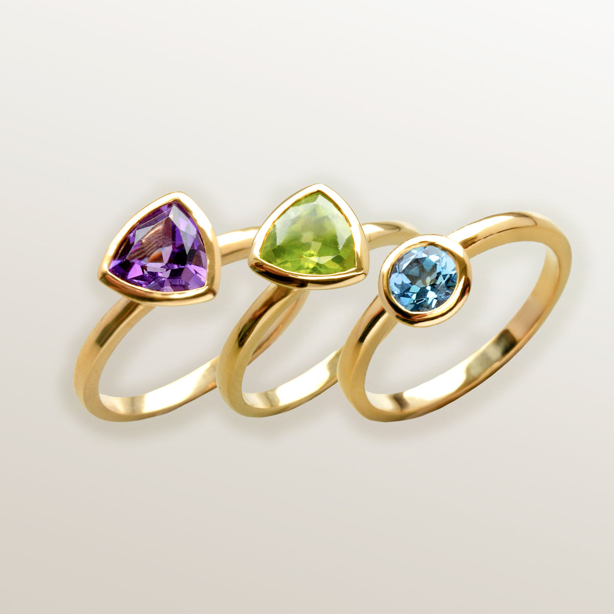 Combinación de 3 anillos de Oro Vermeil amarillo, con piedras amatista natural tallada en forma triangular ("trillion"), peridoto natural en forma triangular ("trillion") y topacio azul brillante.