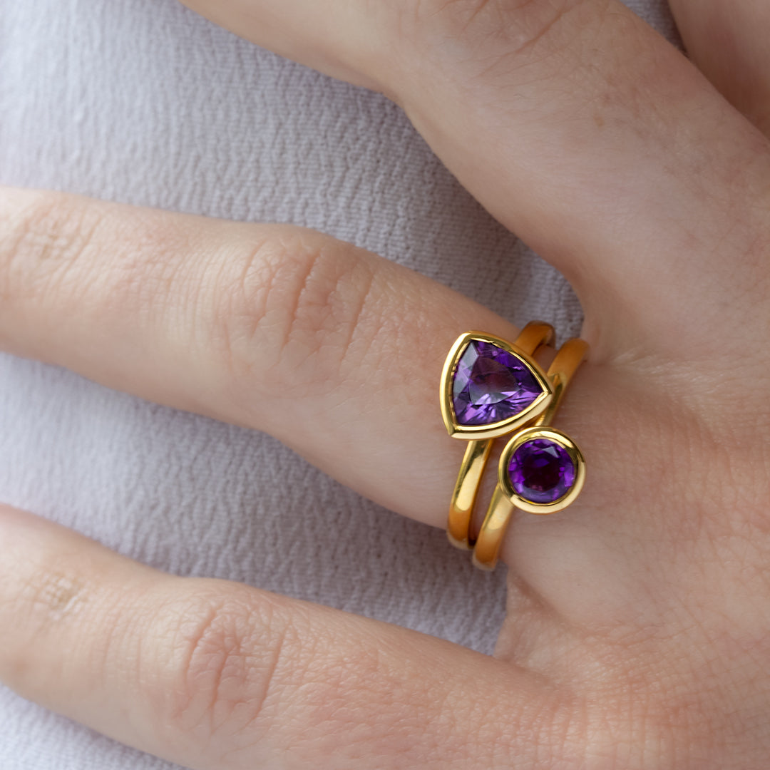 Mano con Combinación de 2 anillos de Oro Vermeil amarillo, con piedras amatista natural tallada en forma triangular y brillante.