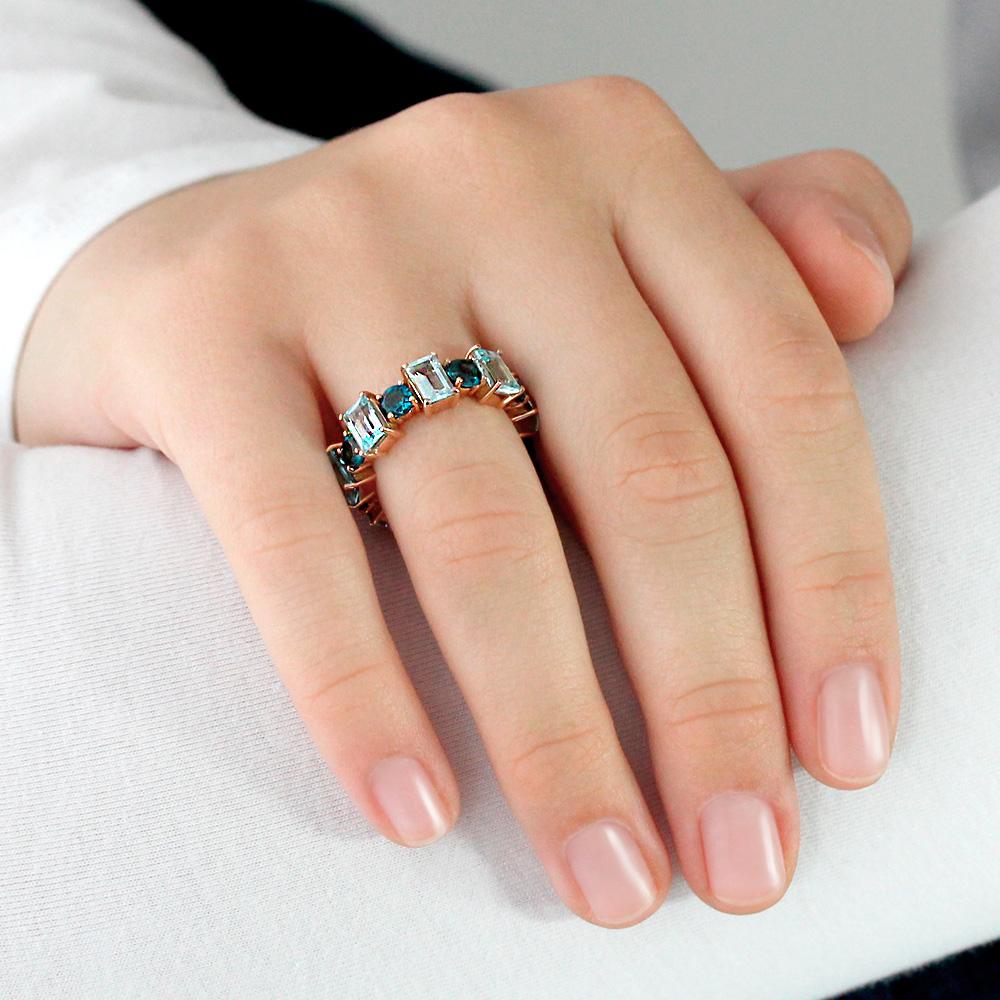 Mano con Anillo tipo eternity de Oro rosa de 750 milésimas. 8 topacios azules naturales de talle octogonal de 6 x 4mm y 8 topacios azules naturales London blue talla redonda afacetada de 4mm.
