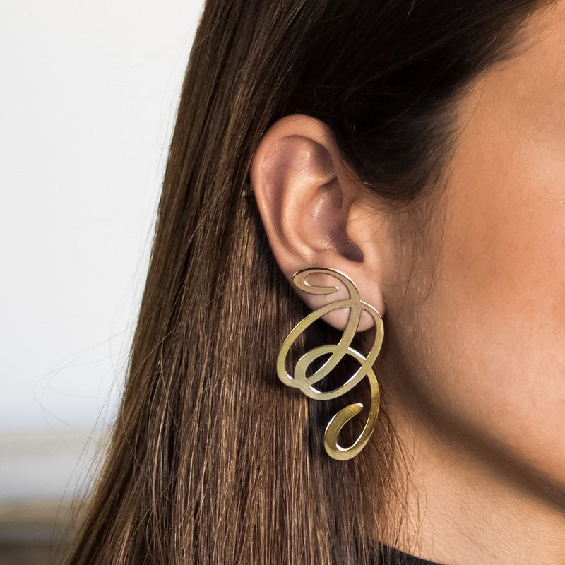 Oreja de modelo luciendo los pendientes largos calados de Oro Vermeil amarillo: plata recubierta de oro amarillo de 18 quilates.