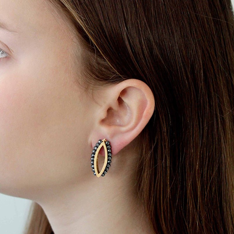 Modelo luciendo los pendientes Oro Vermeil amarillo: Plata de 925 milésimas recubiertos con 3 micras de oro amarillo de 18 quilates.
Rodeados de 18 pequeñas esferas de hematites facetados.