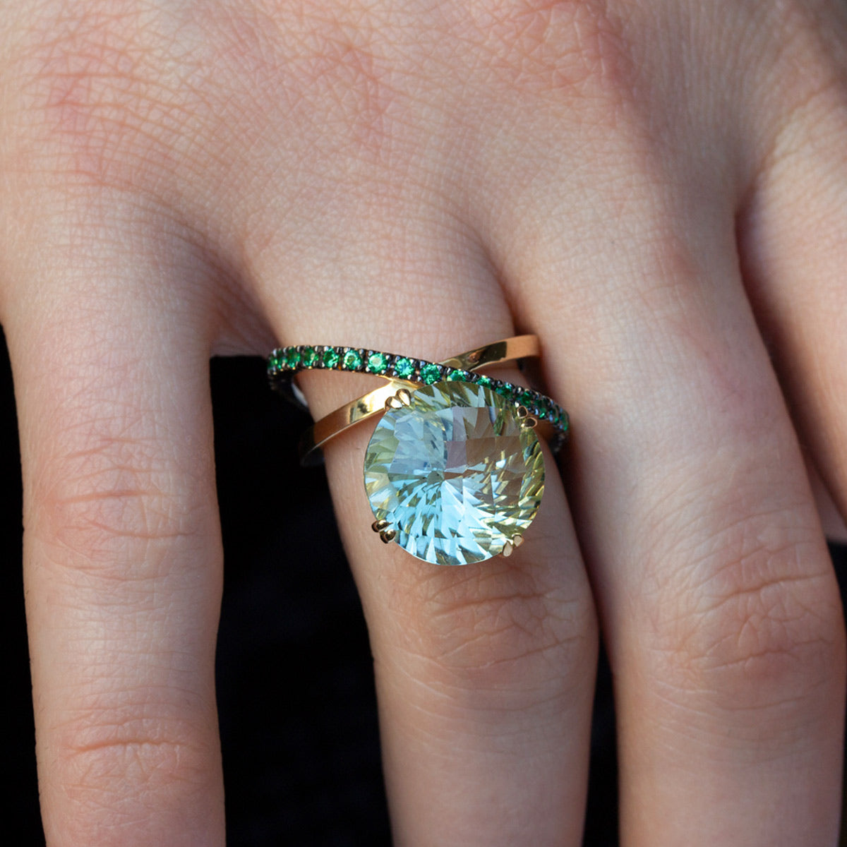 mano de modelo con Anillo de oro amarillo de 750 milésimas con dos órbitas cuajadas de 21 tsavoritas verdes de 2 milímetros y en el centro una gran piedra de Cuarzo verde Prasiolita en talla redonda fantasía.