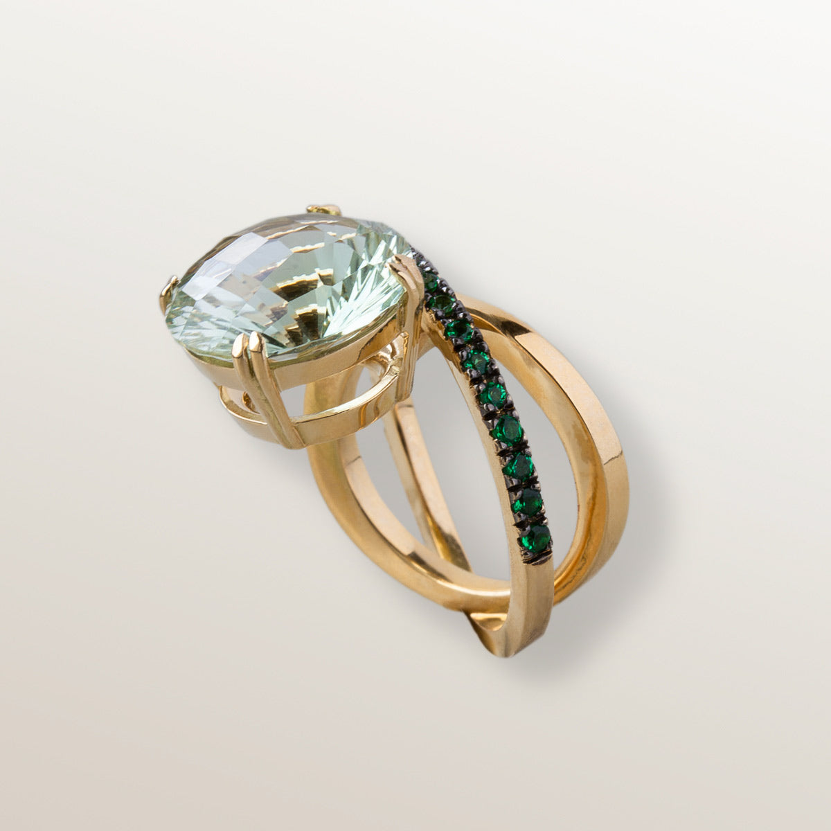 Anillo de oro amarillo de 750 milésimas con dos órbitas cuajadas de 21 tsavoritas verdes de 2 milímetros y en el centro una gran piedra de Cuarzo verde Prasiolita en talla redonda fantasía.