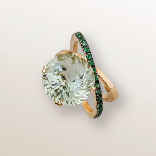 Anillo de oro amarillo de 750 milésimas con dos órbitas cuajadas de 21 tsavoritas verdes de 2 milímetros y en el centro una gran piedra de Cuarzo verde Prasiolita en talla redonda fantasía.