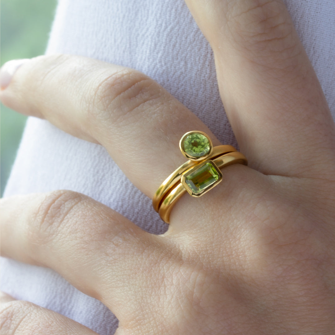 Mano con Combinación de 2 anillos de Oro Vermeil amarillo, con piedras peridoto natural tallada en forma de brillante y octogonal.