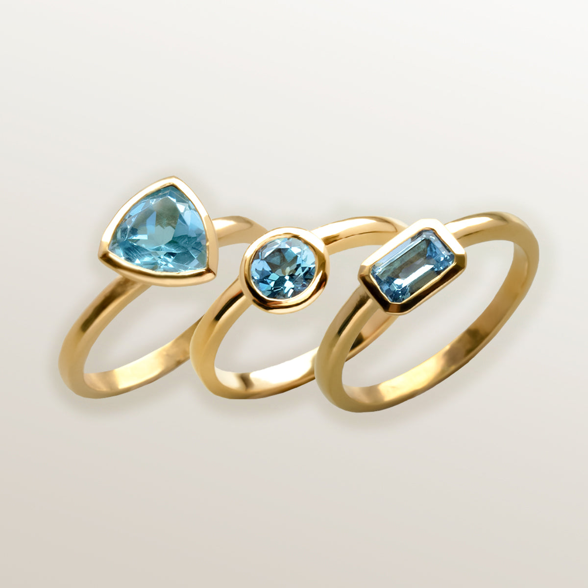 Combinación de 3 anillos de Oro Vermeil amarillo, con piedras topacio azul natural tallada en forma triangular, brillante y octogonal.