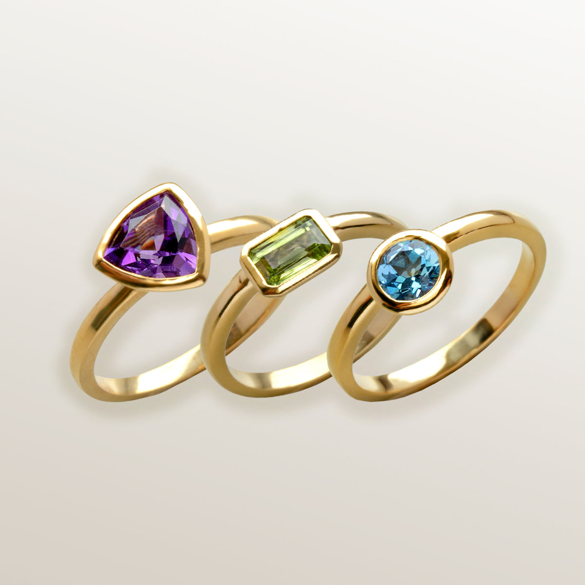 Combinación de 3 anillos de Oro Vermeil amarillo, con piedras amatista natural tallada en forma triangular, peridoto en forma octogonal y topacio azul en forma de brillante.