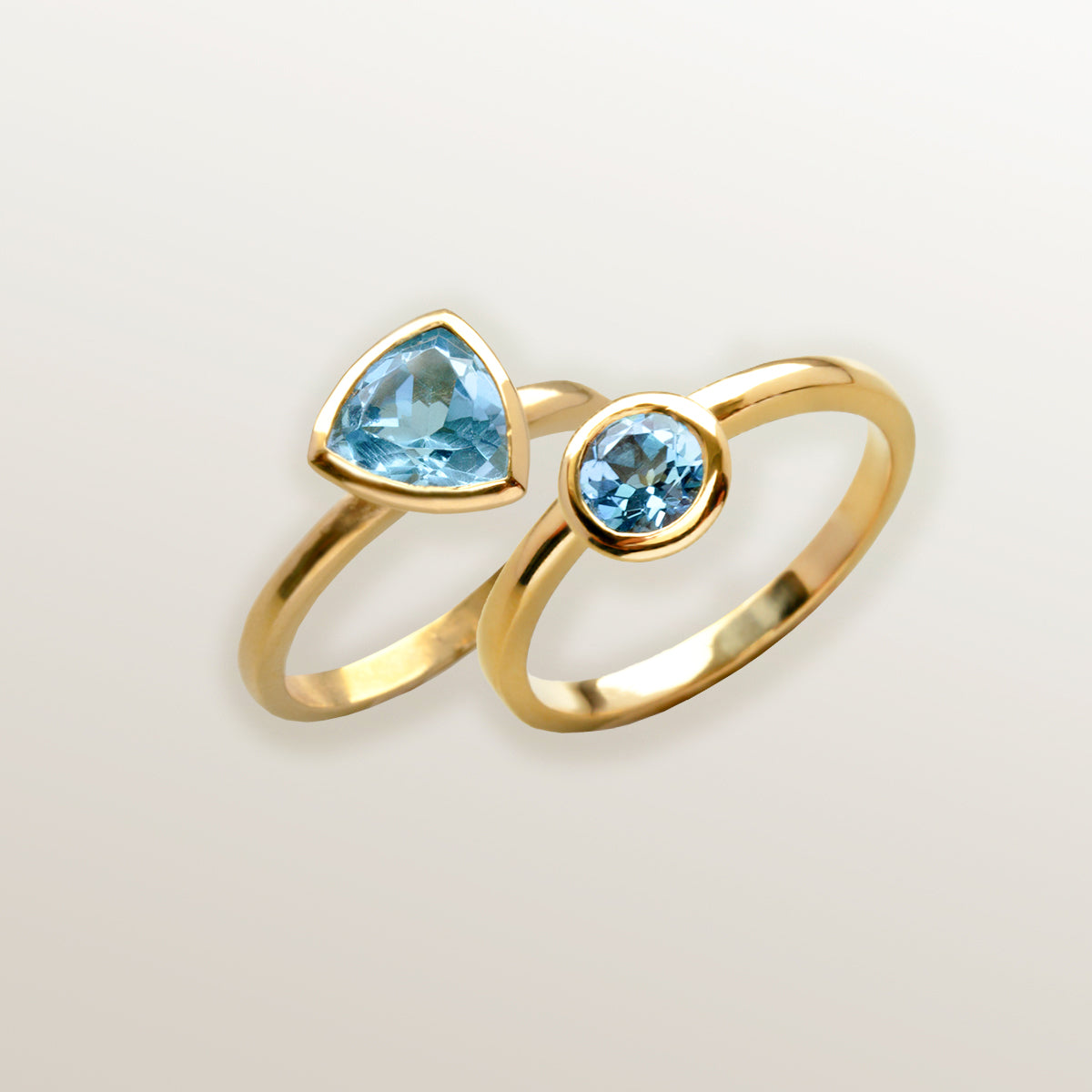 Combinación de 2 anillos de Oro Vermeil amarillo, con piedras topacio azul natural tallada en forma triangular  y brillante.