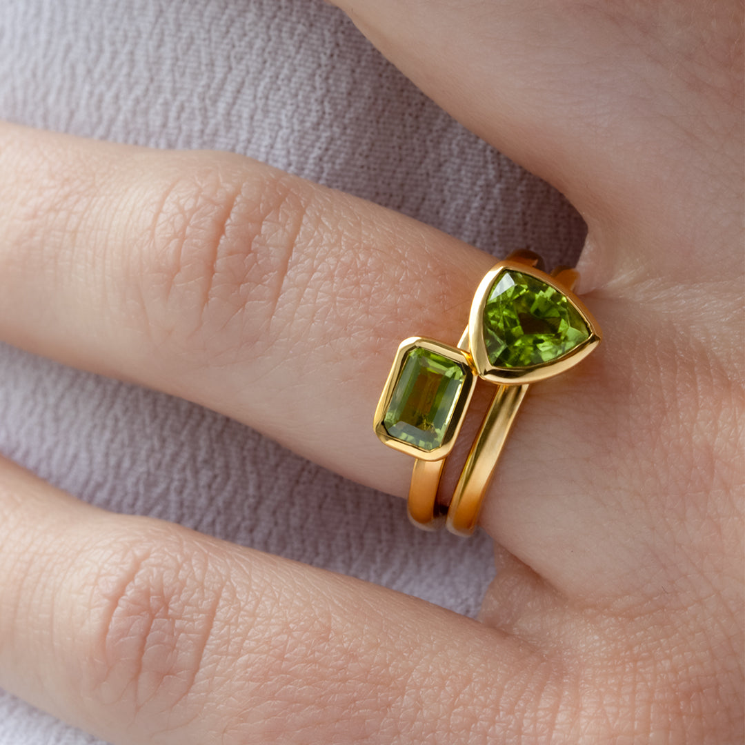 Mano con Combinación de 2 anillos de Oro Vermeil amarillo, con piedras peridoto natural tallada en forma triangular y octogonal.