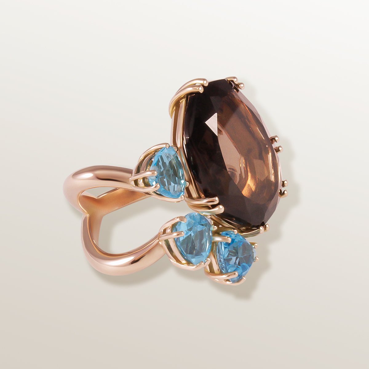 Anillo de oro rosa con aro con forma de hueso de la suerte, cuarzo ahumado talla fantasía y 3 topacios azules triangulares