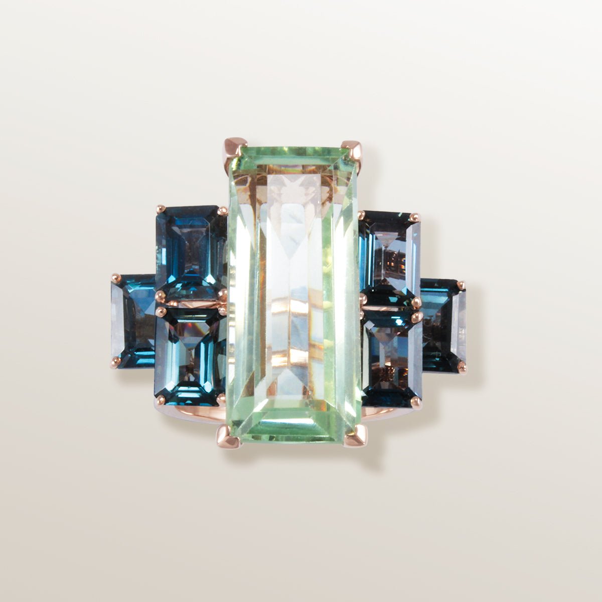 Anillo de oro rosa de 750 milésimas con Prasiolita color verde agua en talla rectangular y 6 piedras laterales Topacio azul variedad London Blue de color azul cobalto.