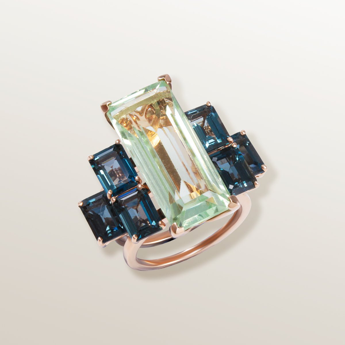 Anillo de oro rosa de 750 milésimas con Prasiolita color verde agua en talla rectangular y 6 piedras laterales Topacio azul variedad London Blue de color azul cobalto.