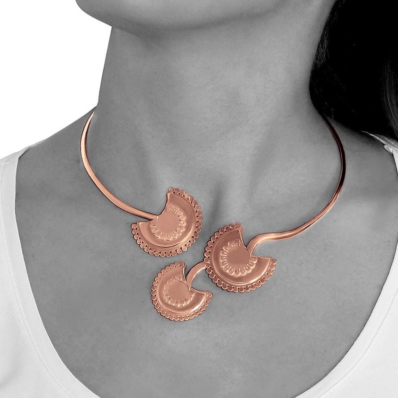 Modelo luciendo el Collar rígido abierto de Oro Vermeil rosa , con tres flores estilizadas elaboradas con corte láser y terminadas a mano.
