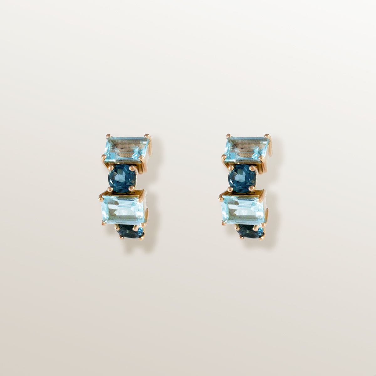 Pendientes tipo medio aro o criolla eternity de oro rosa con topacios azules London blue octogonales y redondos.