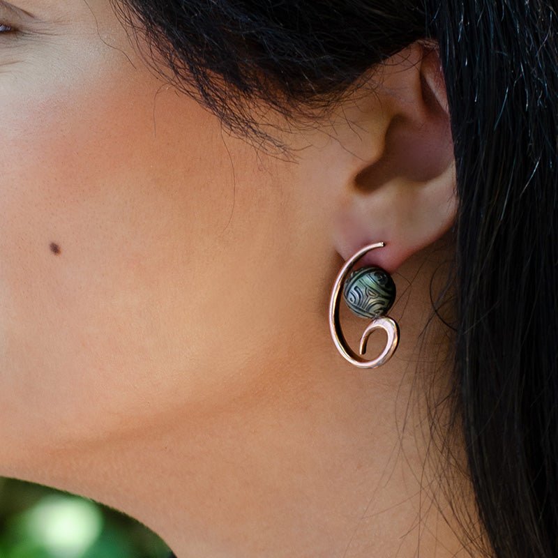 Modelo con Pendientes de Oro Vermeil rosa, con una perla de Tahití grabada con motivos Maorís.